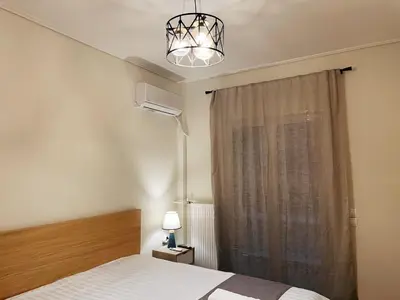 a bedroom with a bed and a chandelier and a window at Bluebay Cozy Aparment 8 in Athens
