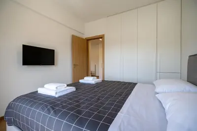 a bedroom with a bed and a flat screen tv at Attiki Square & Metro Modern 2-Bedroom Apt by MPS in Athens