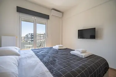 a bedroom with a bed with a tv on the wall at Attiki Square & Metro Modern 2-Bedroom Apt by MPS in Athens