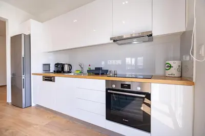 a kitchen with white cabinets and a black oven at Attiki Square & Metro Modern 2-Bedroom Apt by MPS in Athens