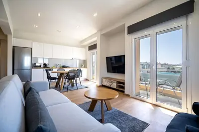 a living room with a couch and a table and a kitchen at Attiki Square & Metro Modern 2-Bedroom Apt by MPS in Athens