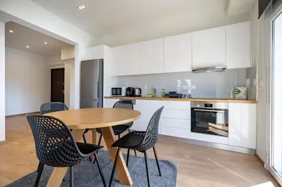 a kitchen and dining room with a wooden table and chairs at Attiki Square & Metro Modern 2-Bedroom Apt by MPS in Athens