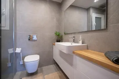 a bathroom with a sink and a toilet and a mirror at Attiki Square & Metro Modern 2-Bedroom Apt by MPS in Athens