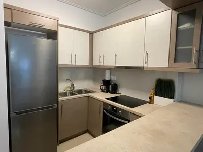 a kitchen with white cabinets and a stainless steel refrigerator at Bluebay comfort apartment 18 in Athens