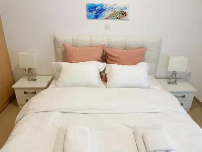 a white bed with pillows and two tables with lamps at Bluebay comfort apartment 18 in Athens