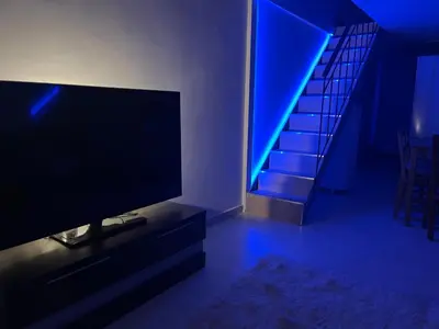 a living room with a tv and a staircase with blue lights at Chic & Cozy Apartment in Gazi, Athens in Athens