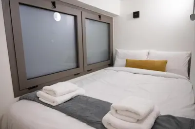 a bed with three towels on it with two windows at 3Bed Loft 500m from Monastiraki Sq in Athens