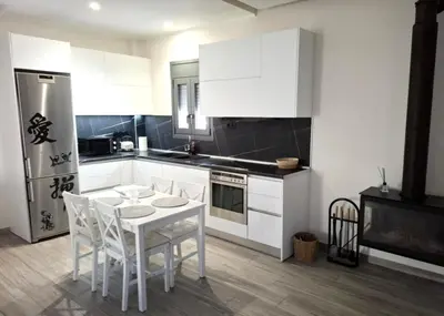 a kitchen with white cabinets and a white table and chairs at Cube House in Athens