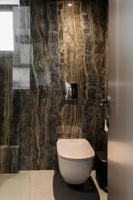 a bathroom with a toilet and a stone wall at Raise Infinity Blue Penthouse in Athens