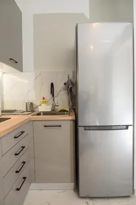 a stainless steel refrigerator in a kitchen with white cabinets at Modern Flat in Exarchia in Athens