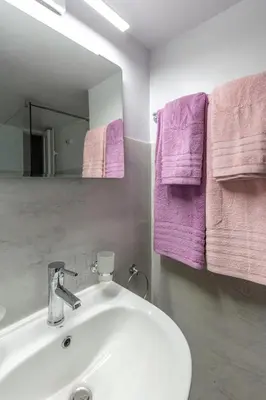 a bathroom with a white sink and purple towels at Stylish Modern Athens apt in Athens