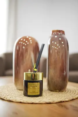 a candle sitting on a table next to two glass jars at ARIS Kallithea- Big & Bright 3 Bedroom Apartment in Athens