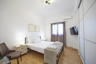 a bedroom with a bed and a chair and a television at ARIS Kallithea- Big & Bright 3 Bedroom Apartment in Athens