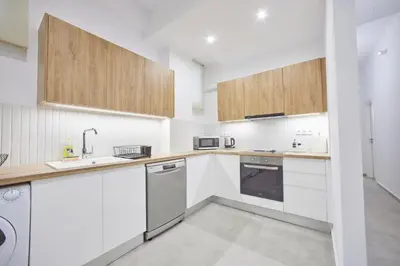 a kitchen with white appliances and wooden cabinets at ARIS Kallithea- Big & Bright 3 Bedroom Apartment in Athens