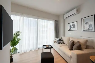 a living room with a couch and a large window at Silk Athens Urban Collection in Athens
