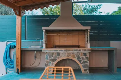 a outdoor oven with a table and a chair at Palm & Spa in Barbaliáki