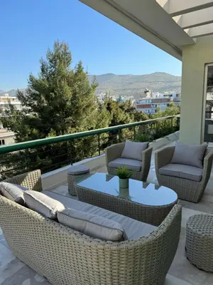 a patio with wicker chairs and tables on a balcony at Glyfada Gorgeous Penthouse in Athens