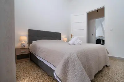 a bedroom with a bed with a white bedspread and a night stand at Sunrise Apartment By Athens Airport in Spáta