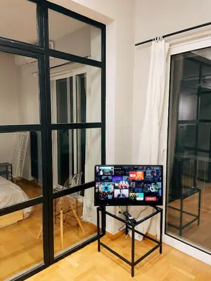 a computer on a stand in a room with windows at Bluebay Cozy apartment 18 in Athens