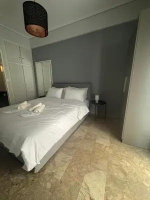 a bedroom with a white bed with two towels on it at Cozy faliro in Piraeus