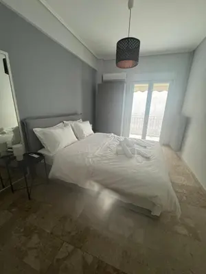 a bedroom with a white bed and a window at Cozy faliro in Piraeus