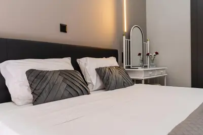 a white bed with two pillows and a mirror at Gkr Luxury Apartments Metro Petralona in Athens