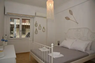 a bedroom with a white bed and a chandelier at Constantine cozy apartment in Piraeus
