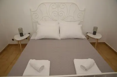 a large bed with white pillows and two tables at Constantine cozy apartment in Piraeus