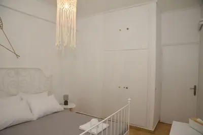 a white bedroom with a bed and a chandelier at Constantine cozy apartment in Piraeus