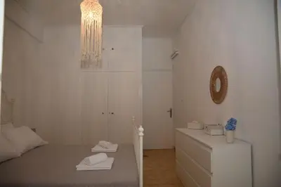 a white bedroom with a bed and a mirror at Constantine cozy apartment in Piraeus