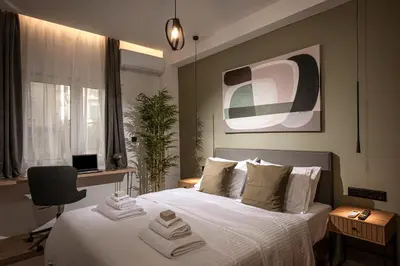 a bedroom with a bed with white sheets and a desk at Asty60 - Cozy Athen's Apartment in Athens