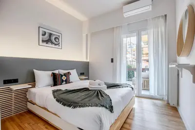 a white bedroom with a bed and a window at Belmont - 2 BR Apartment & Balcony in Athens in Athens