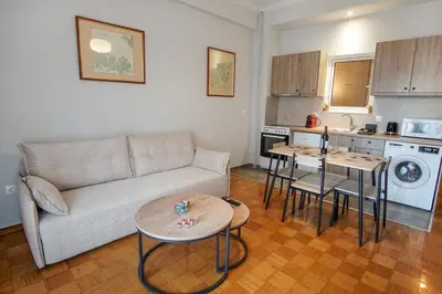 a living room with a couch and tables and a kitchen at Cozy Nest, One-Bedroom Flat in Athens