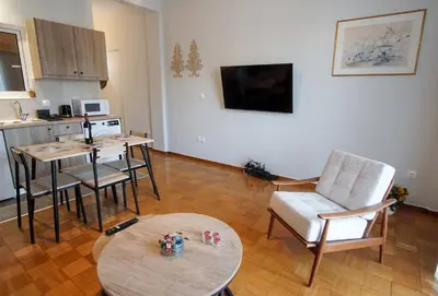 a living room with a table and a kitchen at Cozy Nest, One-Bedroom Flat in Athens