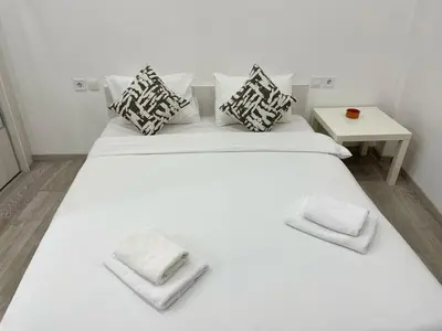 a large white bed with pillows and a side table at Bluebay Cozy Aparment in Athens