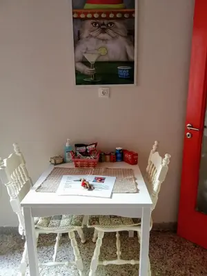 a white table with chairs and a cat picture on the wall at The Happy Town House , 300m from the metro station in Athens