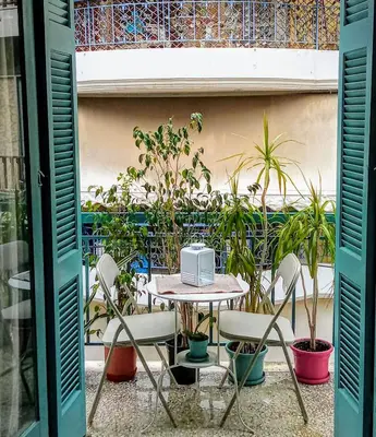 a table and chairs with a laptop on top of it at The Happy Town House , 300m from the metro station in Athens