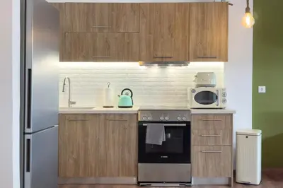 a kitchen with wooden cabinets and a stainless steel refrigerator at Phaedrus Living Kallithea Heights Residence in Athens