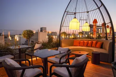 a rooftop patio with a couch and tables and chairs at Adia Aluma Athens, Curio Collection By Hilton in Athens