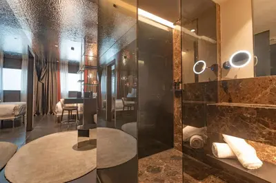 a bathroom with a glass shower and a table at Adia Aluma Athens, Curio Collection By Hilton in Athens