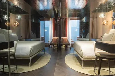 a bedroom with two beds and chairs and windows at Adia Aluma Athens, Curio Collection By Hilton in Athens