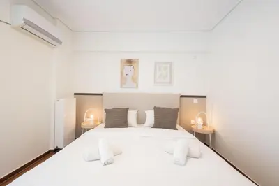 a bedroom with a large white bed with two tables at Seaside Elegance Brand New 2BD Luxury Stay in Athens