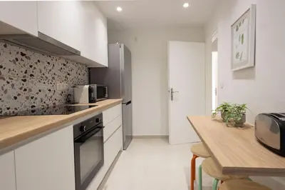 a kitchen with white cabinets and a wooden table at Seaside Elegance Brand New 2BD Luxury Stay in Athens