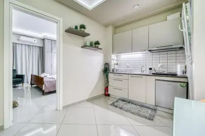 a kitchen with white cabinets and a living room at So36 Filoxenia Place Like Home Kolonaki- next to metro and center in Athens