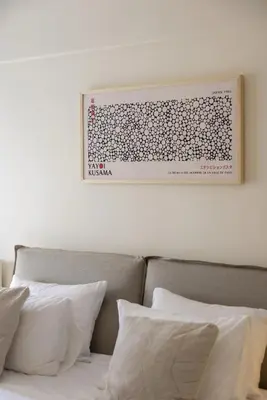 a picture hanging above a bed with white pillows at Renovated Studio with Sea View in Palaio Faliro in Athens