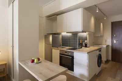 a kitchen with white cabinets and a table with a bowl of fruit at Renovated Studio with Sea View in Palaio Faliro in Athens