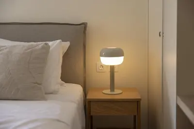 a lamp on a night stand next to a bed at Renovated Studio with Sea View in Palaio Faliro in Athens