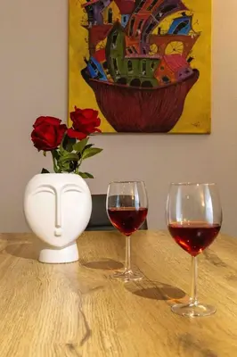 two glasses of red wine and a vase with roses at Tete's Acropolis View Penthouse in Athens