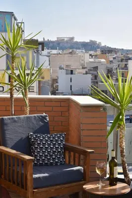 a bench on a balcony with a wine glass and palm trees at Tete's Acropolis View Penthouse in Athens