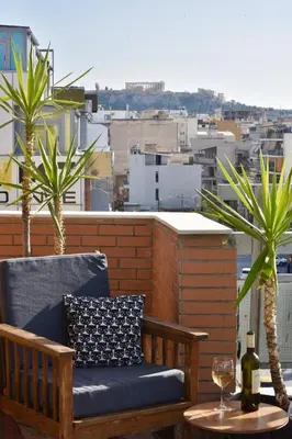 a bench on a balcony with a wine glass and palm trees at Tete's Acropolis View Penthouse in Athens